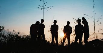 silhouette-group-of-people-standing-on-grass-field-1250346